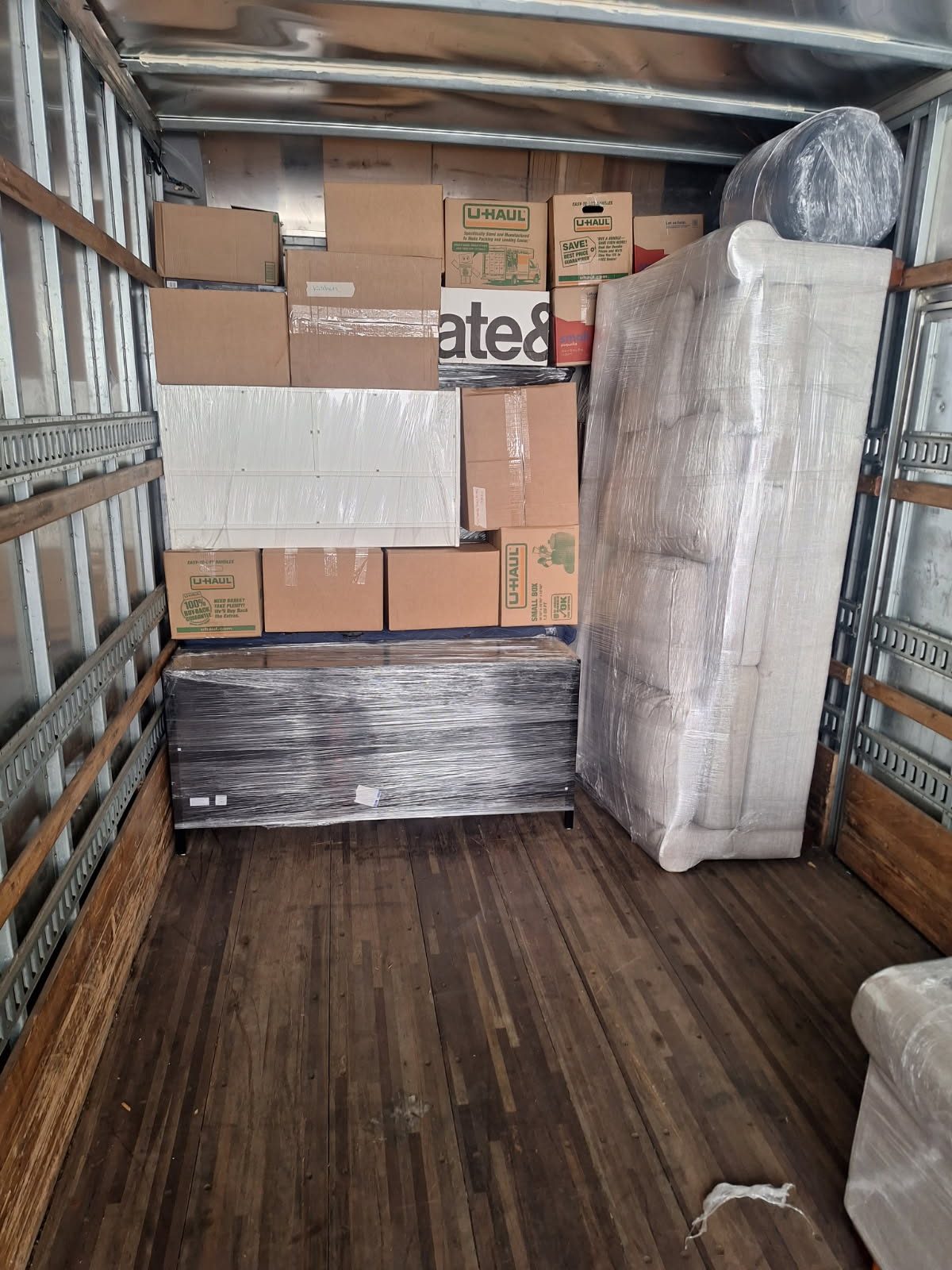 U-Haul moving truck cargo area filled with wrapped furniture and cardboard boxes