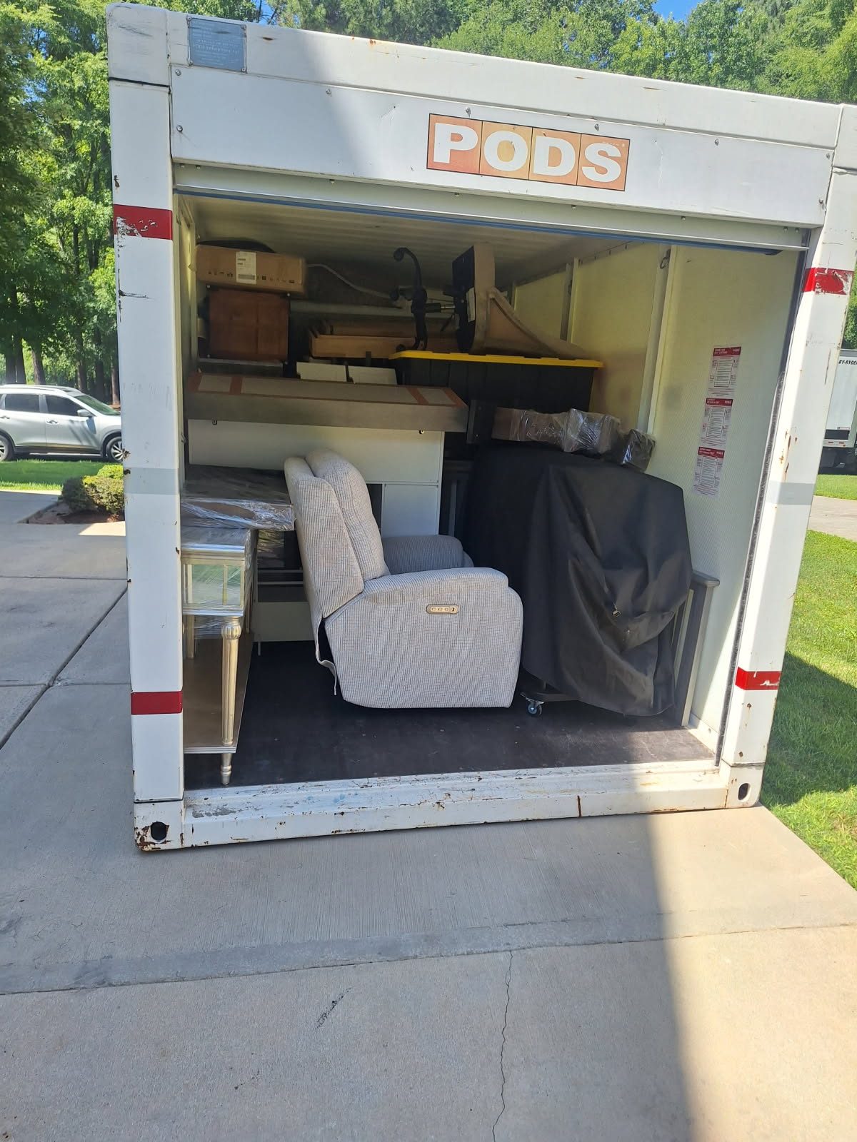 Open PODS moving container filled with furniture and household items on residential street