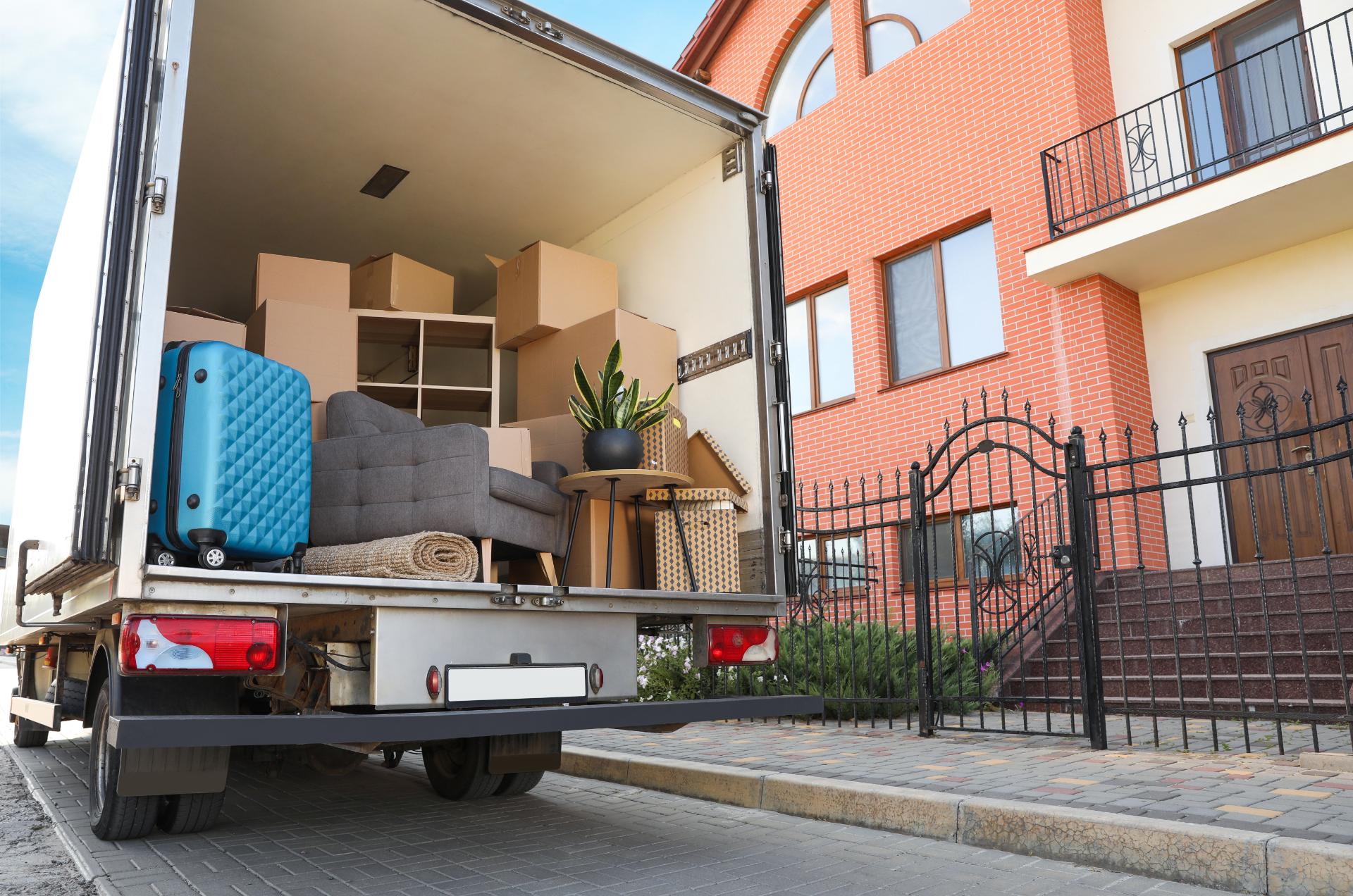 Moving truck loaded with furniture parked outside brick residential building